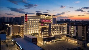 A multi-story hotel with a prominent entrance and a parking area. - Huakang International Hotel (Qianjiang)