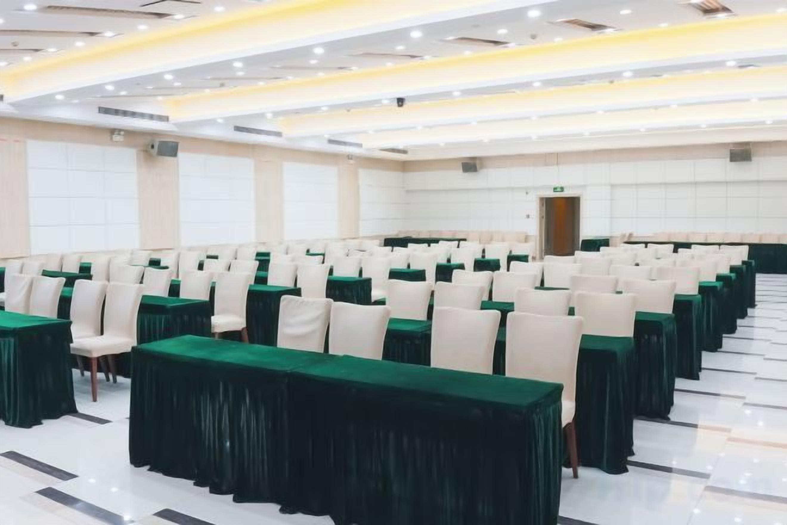 A conference room with rows of tables and chairs, a polished floor, and a bright ceiling.
