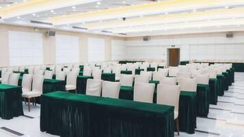 A conference room with rows of tables and chairs, a polished floor, and a bright ceiling.