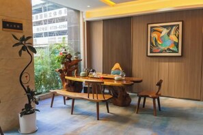 Un comedor con una mesa y sillas de madera, una planta en maceta y un cuadro en la pared.