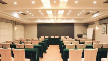 A conference room with rows of chairs, a stage, and a projector screen.