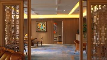 A room with a traditional Asian-style partition, a dining area with chairs, and a large abstract painting on the wall.