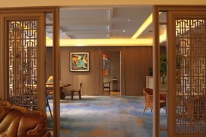 Una habitación con un separador de estilo asiático tradicional, un área de comedor con sillas y un cuadro abstracto grande en la pared.