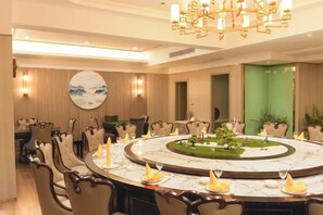 Un salón de conferencias con una mesa redonda, sillas y un candelabro.