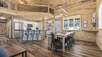 A spacious cabin interior with a kitchen, dining area, and a loft bedroom.