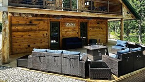 Une cabane en bois dotée d’un balcon, d’une terrasse couverte avec des meubles en osier, et d’une pancarte sur laquelle on peut lire : « Détendez-vous, relaxez-vous et profitez de l’instant présent ».