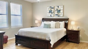 Une chambre à coucher avec un lit en bois, deux tables de chevet, un ventilateur de plafond et des œuvres d’art accrochées au mur.