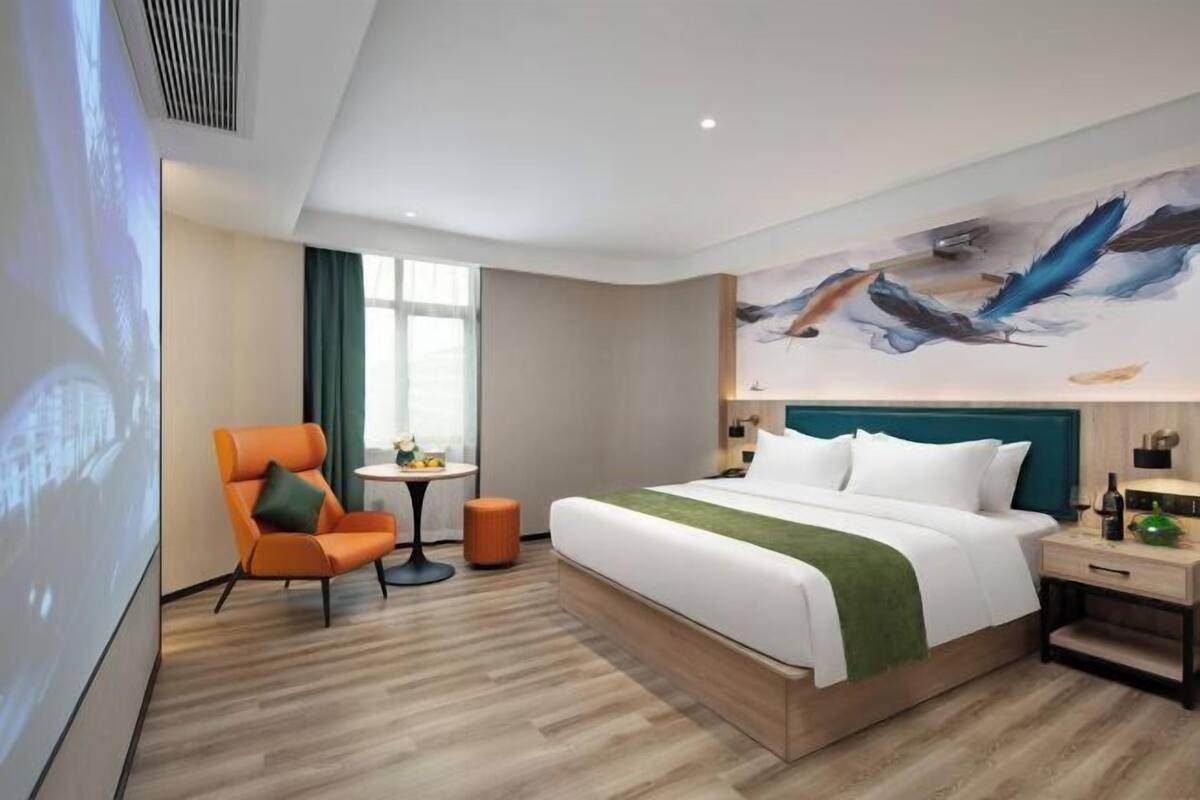 Een moderne hotelkamer met een groot bed, een bureau, een stoel en een schilderij aan de muur.