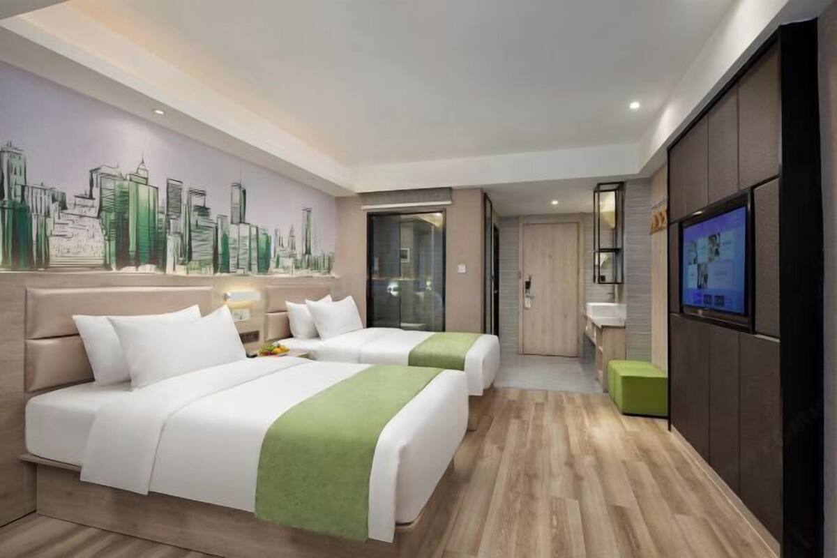 Een hotelkamer met twee bedden, een stadsgezicht muurschildering, een televisie en een badkamer.