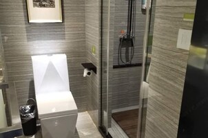 Un bagno moderno con box doccia in vetro, un water e un piccolo ripiano.