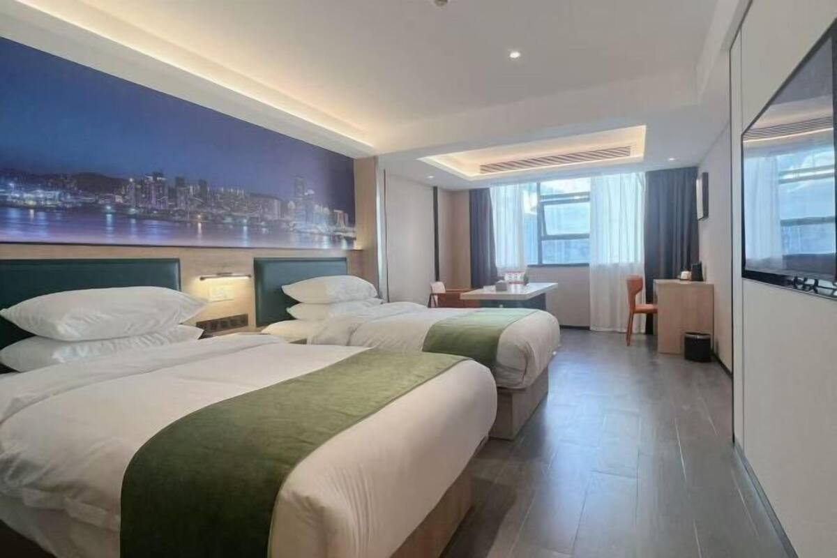 Een hotelkamer met twee bedden, een bureau, een stoel en een groot raam.