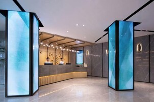 A modern reception area with a curved desk, two staff members, and a digital display.