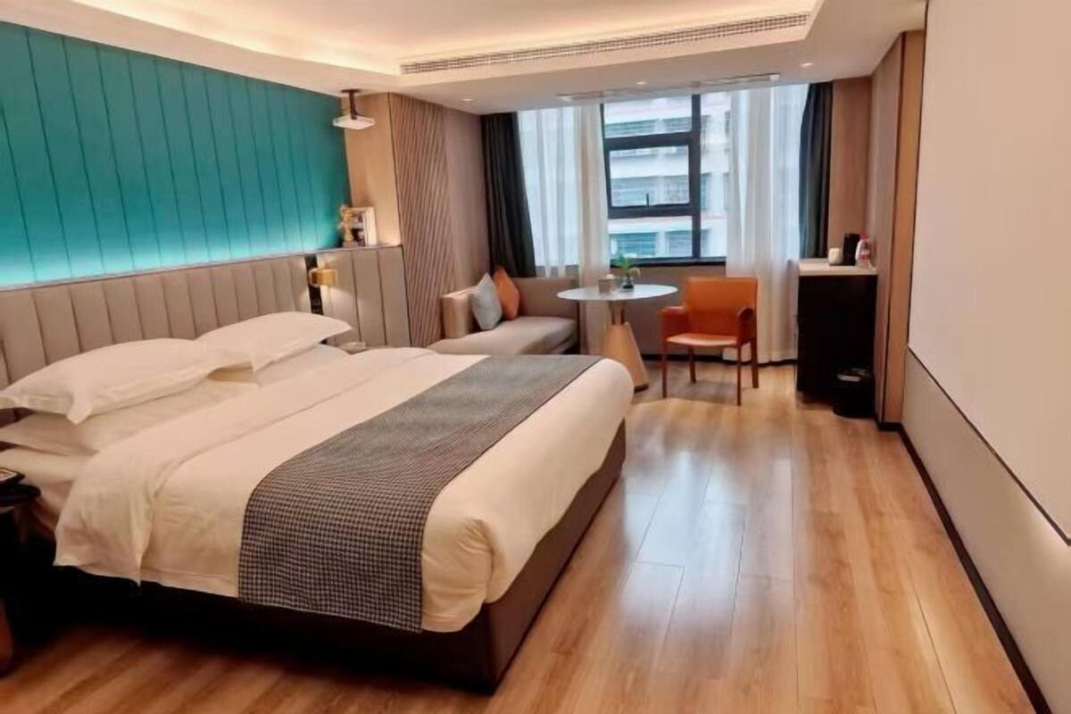 Een hotelkamer met een groot bed, een bank, een klein rond tafeltje en een stoel.
