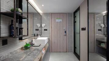 Un baño moderno con encimera de mármol, puerta de madera y cabina de ducha de vidrio.
