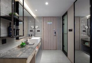 Un bagno moderno con un piano lavabo in marmo, una porta in legno e un box doccia in vetro.