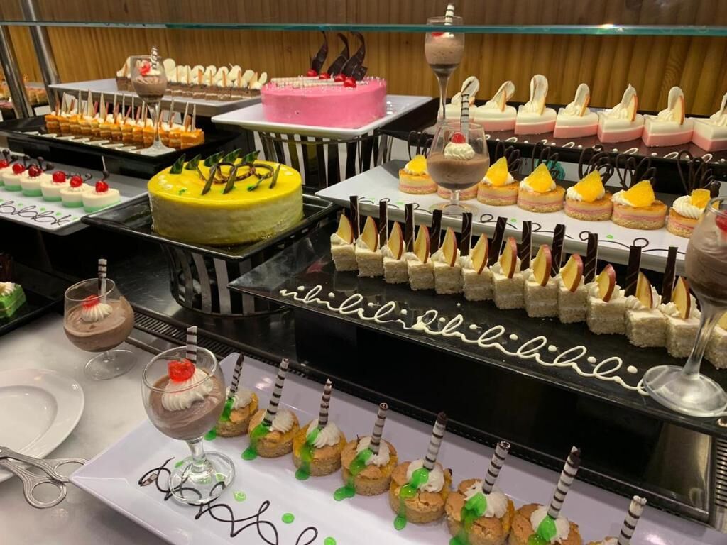 A buffet with various desserts including cakes, cupcakes, and fruit tarts.
