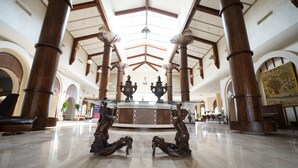 Un vestíbulo espacioso con techos altos, grandes columnas de madera y un mostrador de recepción central.
