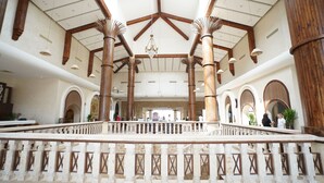 Un hallo espacioso con techos altos, vigas de madera y un candelabro central.