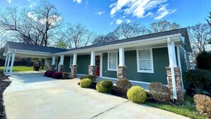 A two-story house with a covered front porch, stone pillars, and a well-maintained lawn. - Relaxing Stay on Trade Street (Greer)