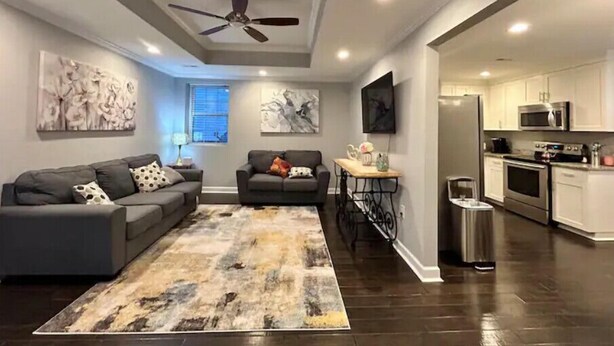 A modern living room with a gray sofa, a coffee table, and artwork on the walls. - Relaxing Stay on Trade Street (Greer)