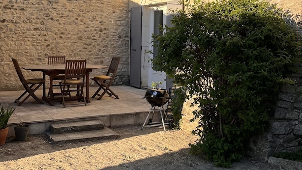 A stone building with a patio, outdoor seating, and a grill.