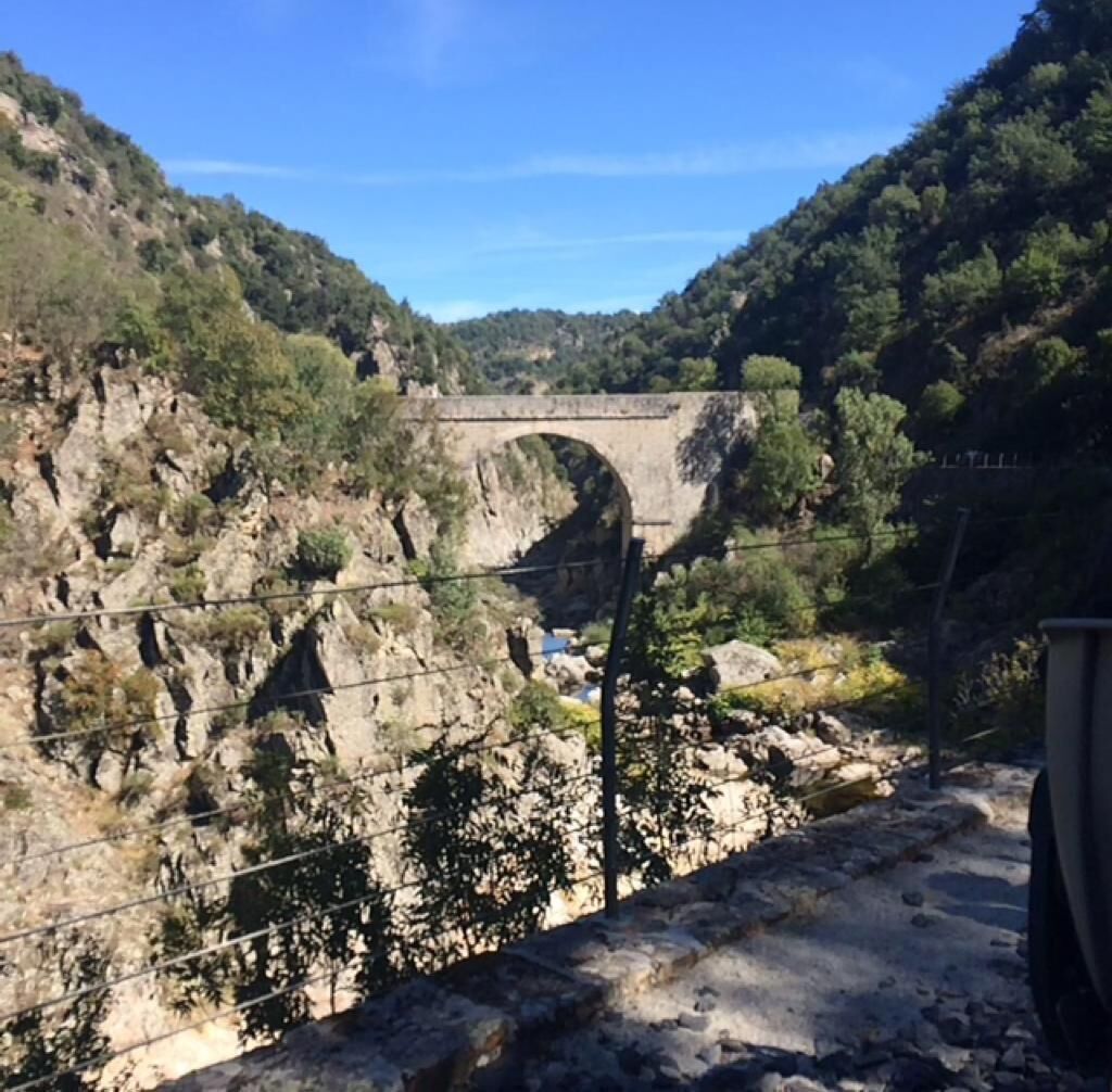A stone bridge over a rocky gorge with a clear blue sky.