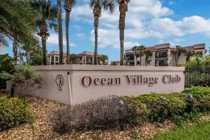 Experience the tropical setting of Ocean Village Club, surrounded by lush greenery and palm trees, with multiple-story buildings featuring spacious balconies.