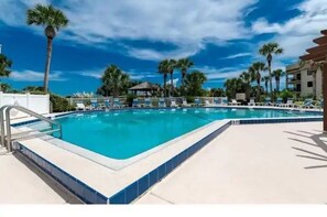 Relax by the pool surrounded by palm trees and lounge chairs.
