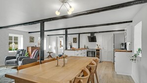A modern kitchen with a central island, wooden dining table, and chairs.
