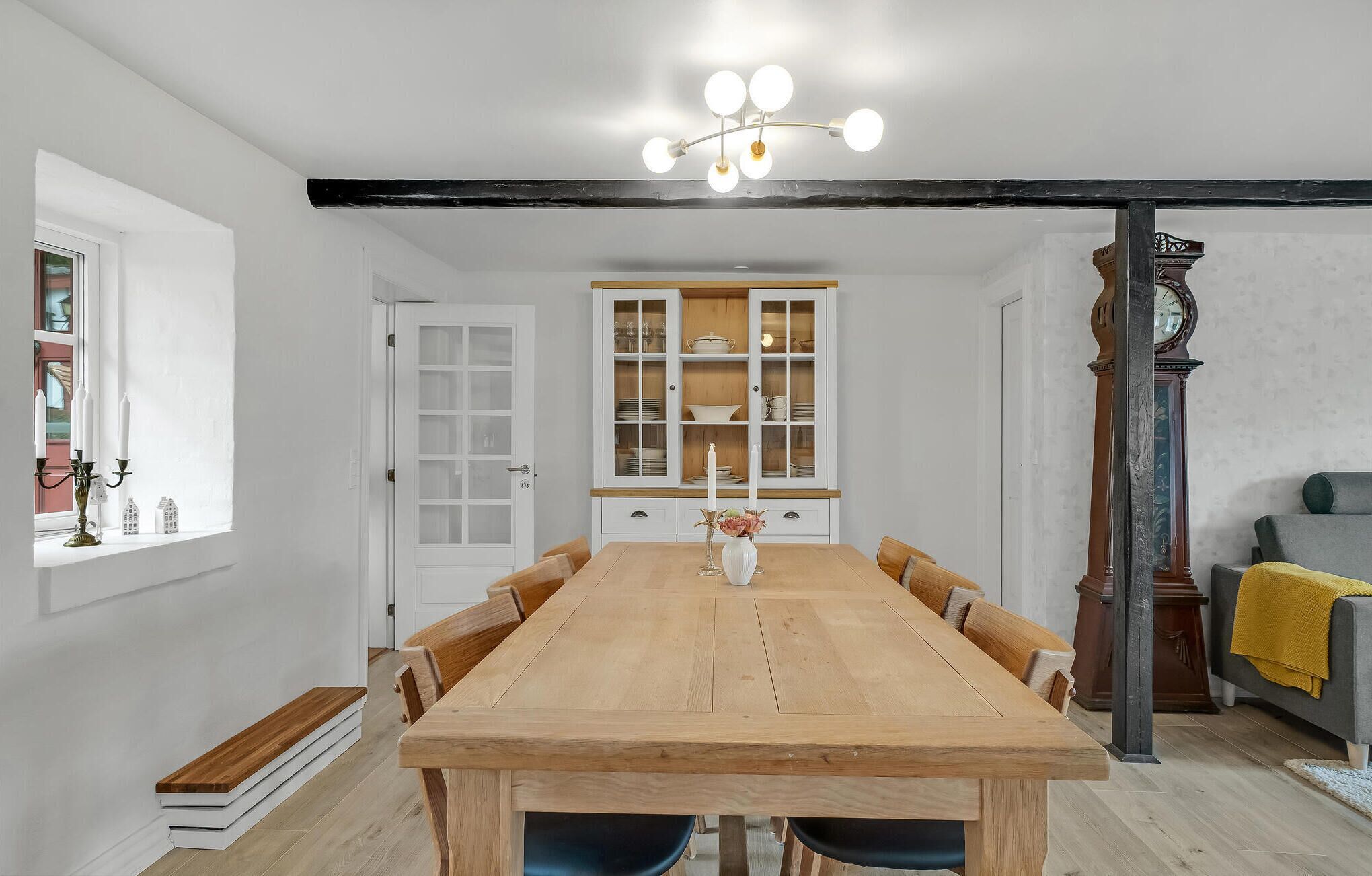 Comedor con mesa de madera, sillas, una alacena con puertas de vidrio y un candelabro.
