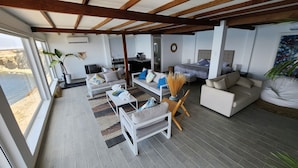 A spacious living area with a high ceiling, a dining area, and a bedroom. - HOTEL BOUTIQUE ATENAS  (Paracas)