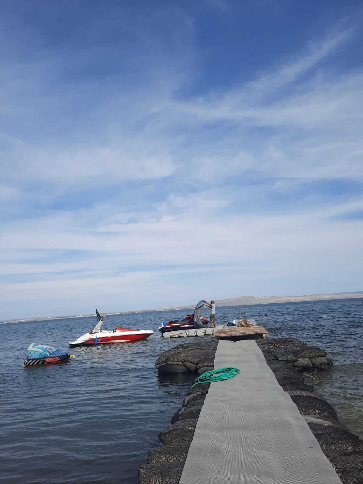 A pier extending into calm water with a clear sky above.