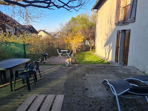 A backyard with a wooden deck, a barbecue grill, and a table with chairs. - Entire house, quiet and at the gates of Annecy (Annecy)
