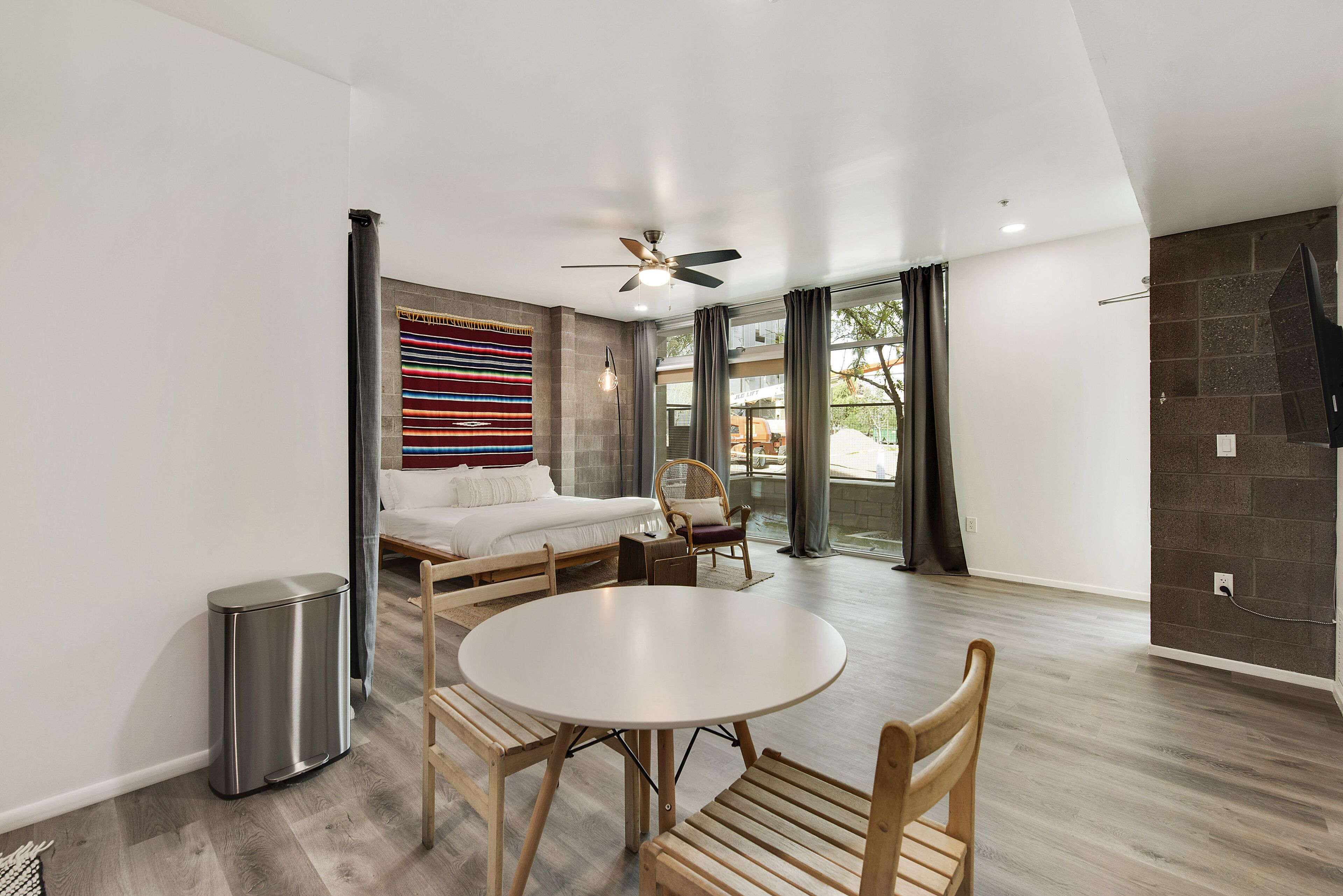 A modern living room with a round table, wooden chairs, a sofa, and a ceiling fan.