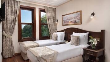 A hotel room with two beds, a large window, a painting, and a nightstand with a vase of flowers.