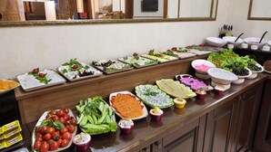 Een buffet met diverse soorten eten, zoals salades, fruit en dipsauzen.