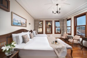 A hotel room with two beds, a chandelier, large windows, and a view of the city. - Bender Hotel (Istanbul)