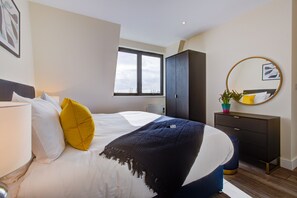 Et moderne hotelværelse med seng, kommode, spejl og et vindue.