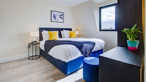 A modern bedroom with a bed, bedside table, and a window. - Charming 2-bed Apartment in Cheam, Sutton (Sutton)