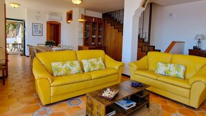 Ein Wohnzimmer mit zwei gelben Sofas, einem Holztisch und einer Treppe im Hintergrund.