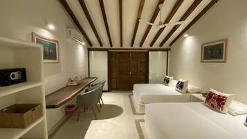 Un dormitori amb escriptori, dos llits, ventilador de sostre i armari amb portes corredisses.