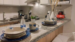 A kitchen counter with various dishes, a water bottle, a potted plant, and a red bag. - LOFT LIMA -Depa- Magdalena del Mar (Lima)