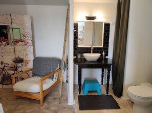 Un baño con una silla de madera, un lavamanos, un espejo y un inodoro.