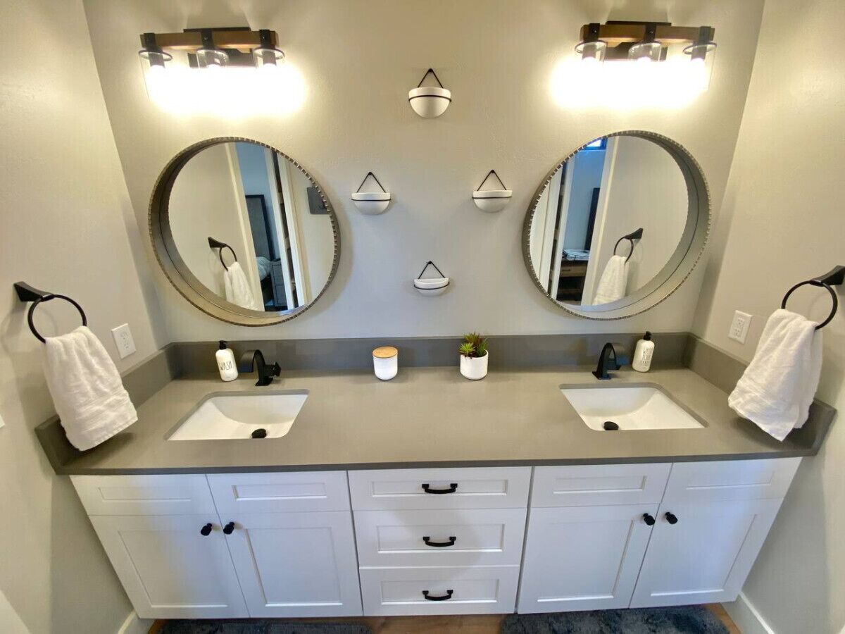 A bathroom with two sinks, a mirror above each sink, and a towel rack with towels.