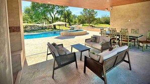 An outdoor patio area with a pool, wicker furniture, and a stone fire pit. - Tree Top Retreat-Pool-Playground-Brewery (Dripping Springs)