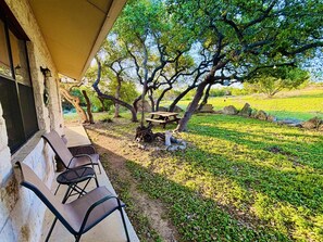 Un patio con mobiliario exterior, una mesa de picnic y una parrilla.