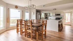 A spacious kitchen with a central island, wooden chairs, and a view of the outdoors.