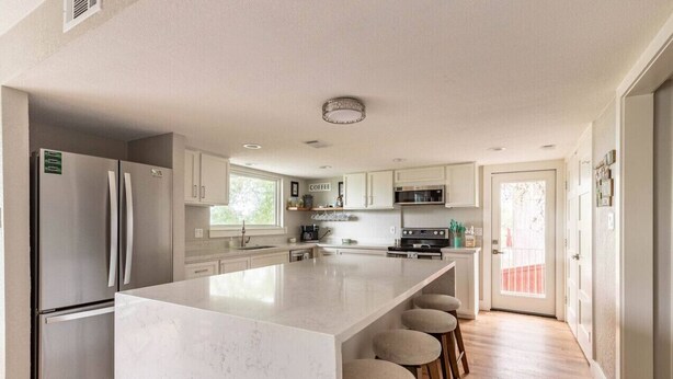 A modern kitchen with a large island, stainless steel appliances, and a bright, airy atmosphere.