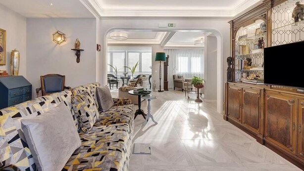 A spacious living room with a patterned sofa, a television, and a decorative cabinet. - Impeccable 4-bed House in São Domingos de Rana (Cascais)