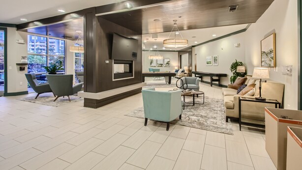 A spacious living area with a large window, a seating area with a sofa and chairs, and a dining area with a table and chairs.